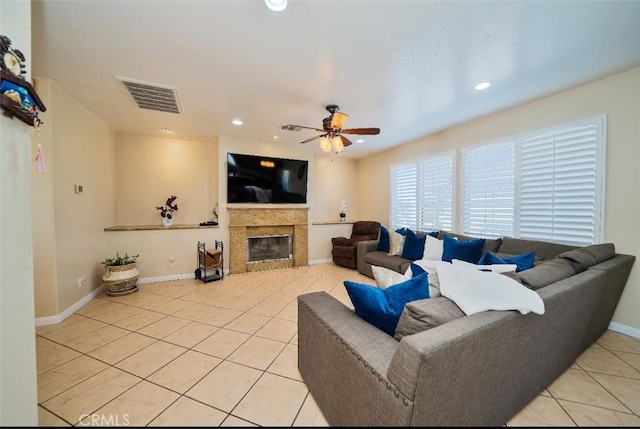 tiled living room with ceiling fan and a tile fireplace