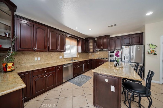 kitchen featuring light stone countertops, sink, stainless steel appliances, a breakfast bar, and light tile patterned flooring