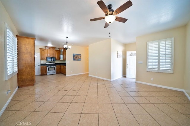 unfurnished living room featuring plenty of natural light, light tile patterned floors, and ceiling fan with notable chandelier