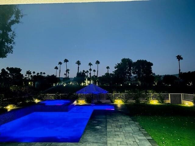 pool at dusk with an in ground hot tub