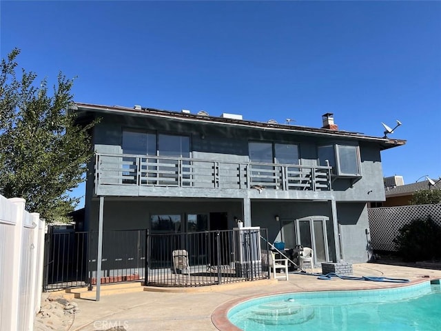 back of property featuring a fenced in pool, a balcony, and a patio area