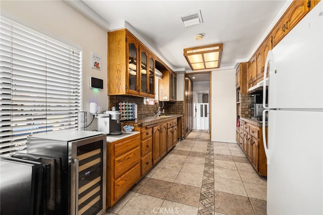 kitchen with light tile patterned floors, beverage cooler, white fridge, and tasteful backsplash