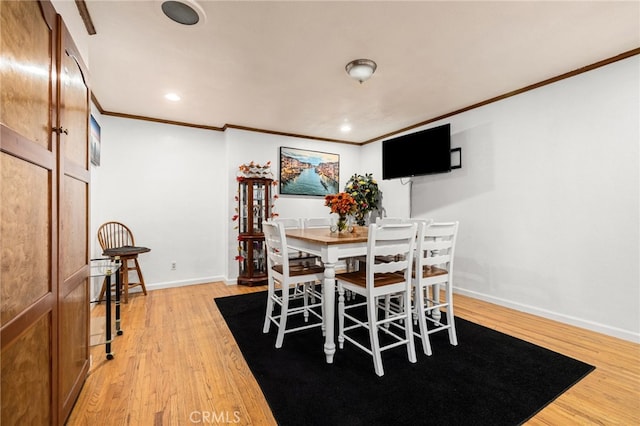 dining space featuring light wood-type flooring and ornamental molding