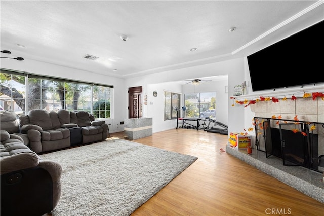 living room with ceiling fan, hardwood / wood-style flooring, plenty of natural light, and a tile fireplace