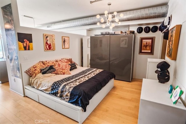 bedroom with a notable chandelier and light wood-type flooring