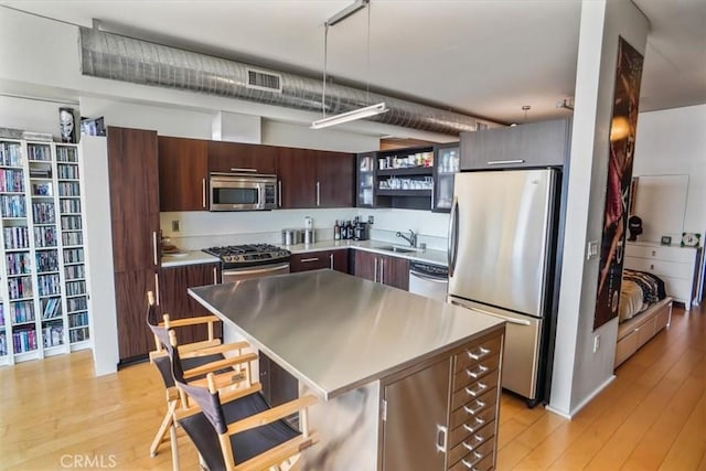 kitchen featuring sink, light hardwood / wood-style flooring, decorative light fixtures, dark brown cabinetry, and stainless steel appliances