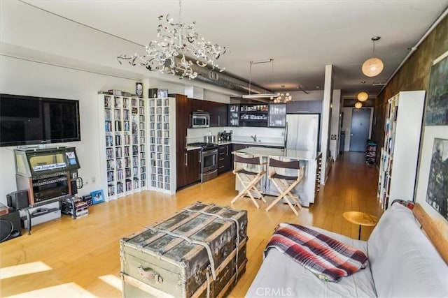 living room featuring a chandelier, sink, and light hardwood / wood-style flooring