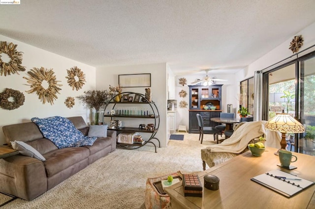 carpeted living room featuring ceiling fan and a textured ceiling