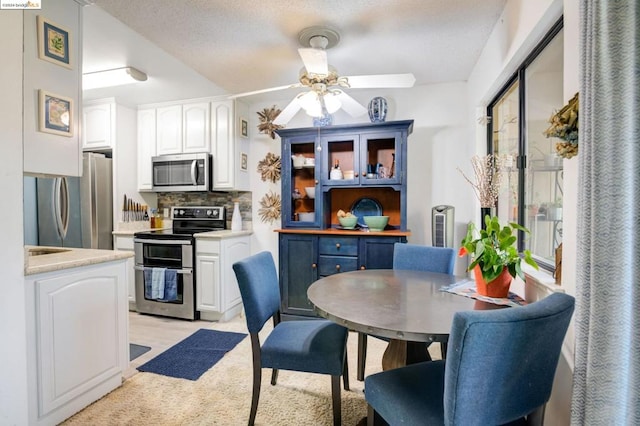 kitchen with ceiling fan, white cabinetry, appliances with stainless steel finishes, light colored carpet, and decorative backsplash