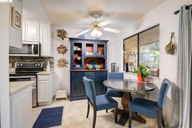 dining room with ceiling fan, light colored carpet, and a textured ceiling