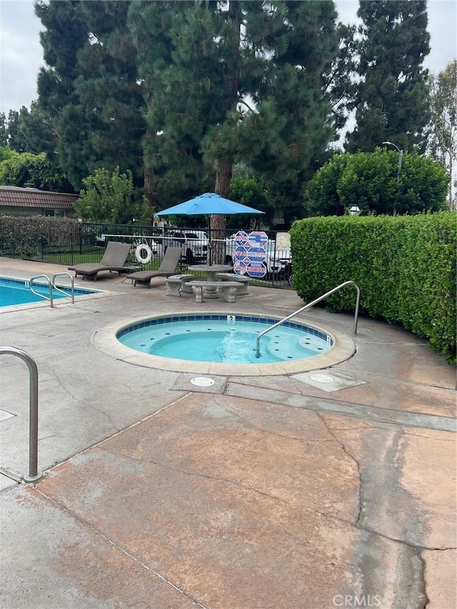 view of swimming pool with a hot tub and a patio area