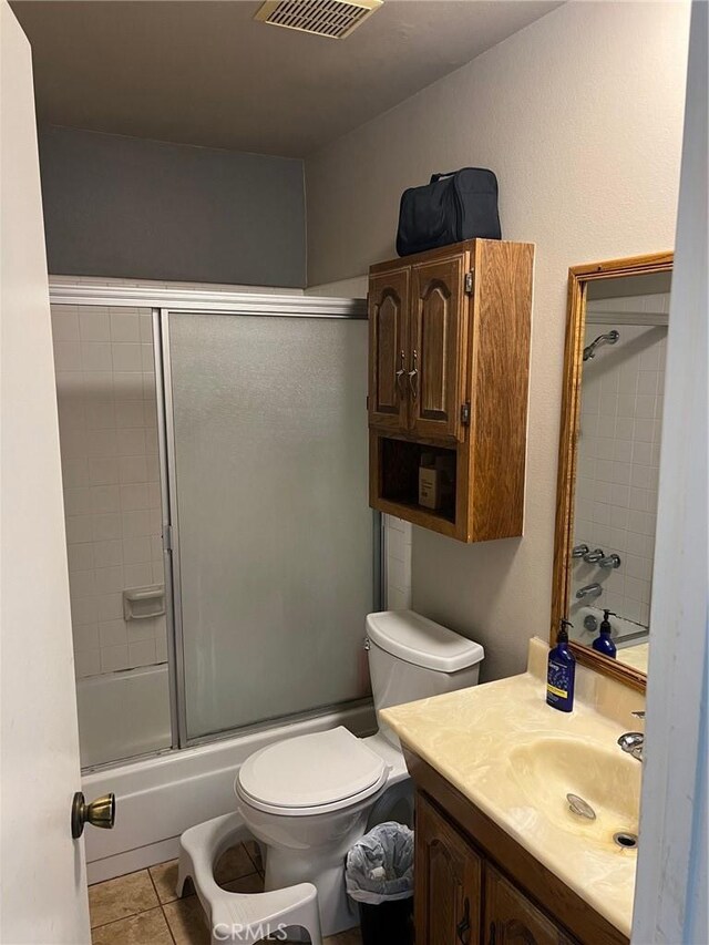 full bathroom featuring tile patterned flooring, vanity, toilet, and bath / shower combo with glass door