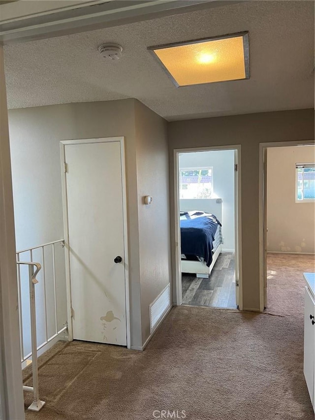 corridor with carpet floors and a textured ceiling