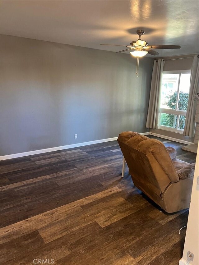 living area featuring ceiling fan and dark wood-type flooring