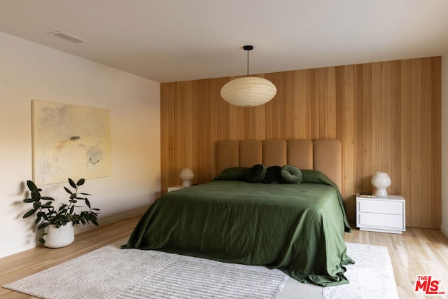 bedroom with hardwood / wood-style flooring and wooden walls