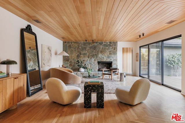 living room with a stone fireplace, wood ceiling, and light hardwood / wood-style floors