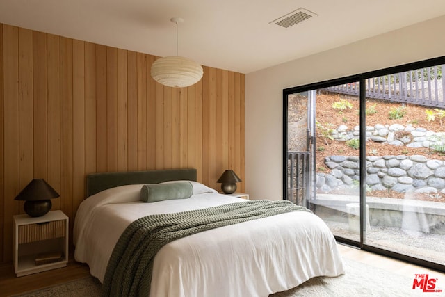 carpeted bedroom featuring access to exterior and wooden walls