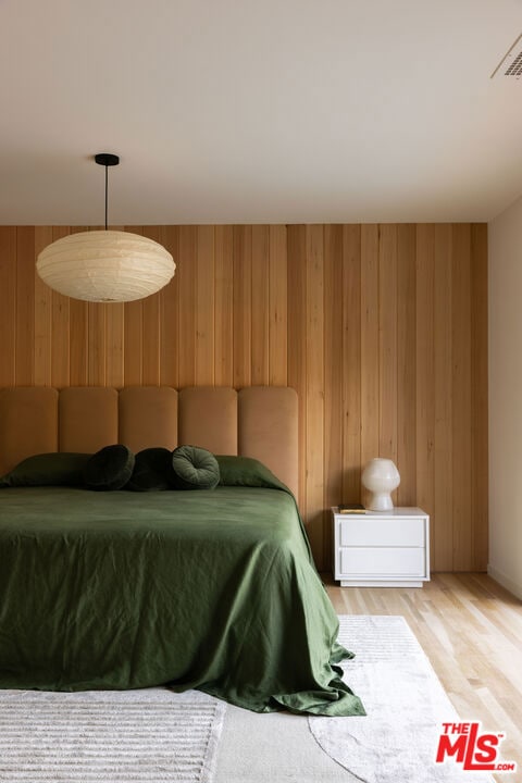 bedroom featuring hardwood / wood-style flooring and wood walls