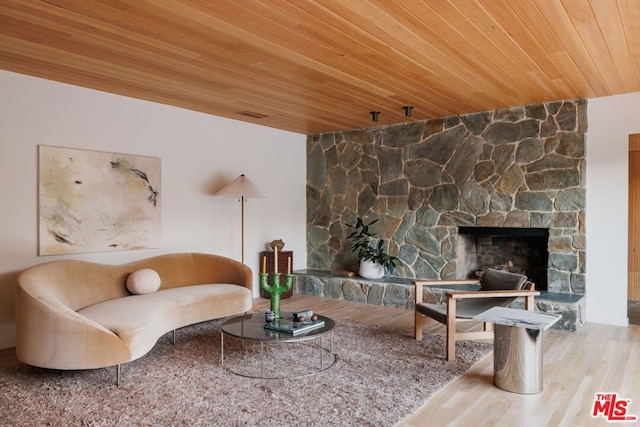 living room with a stone fireplace, hardwood / wood-style floors, and wooden ceiling