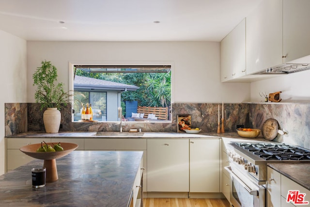 kitchen with white cabinetry, sink, high end white range, and light wood-type flooring