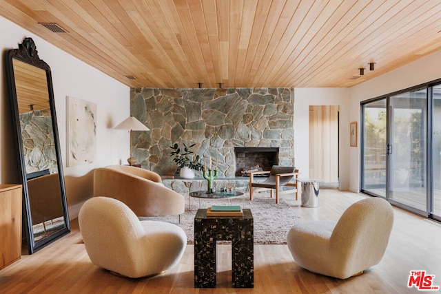 living room featuring french doors, light hardwood / wood-style floors, a stone fireplace, and wood ceiling