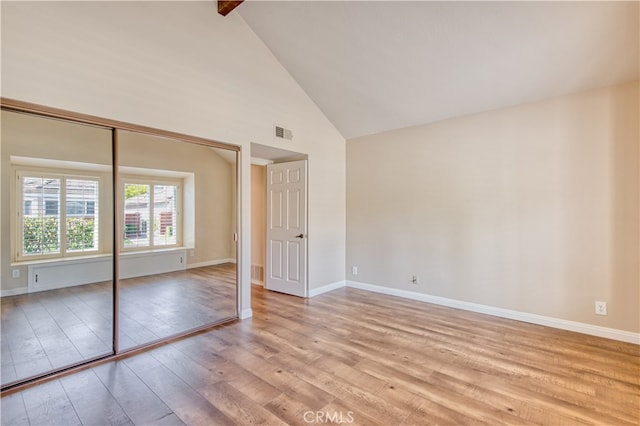 unfurnished bedroom featuring light hardwood / wood-style flooring, a closet, and high vaulted ceiling