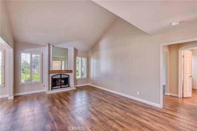 unfurnished living room featuring a healthy amount of sunlight, wood-type flooring, high vaulted ceiling, and a fireplace