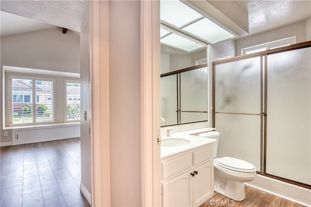 bathroom with lofted ceiling, a shower with shower door, hardwood / wood-style floors, vanity, and toilet