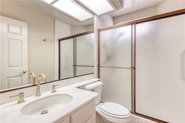 bathroom featuring a shower with door, vanity, and toilet