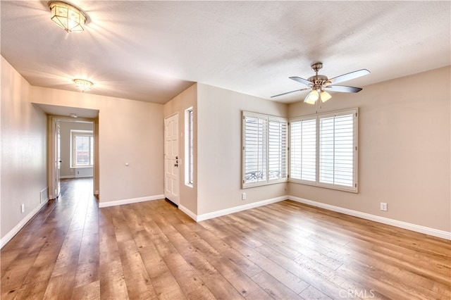 unfurnished room featuring light wood-type flooring, ceiling fan, and a textured ceiling