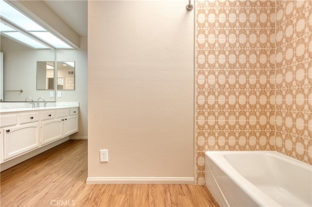 bathroom with vanity, hardwood / wood-style floors, and a bath