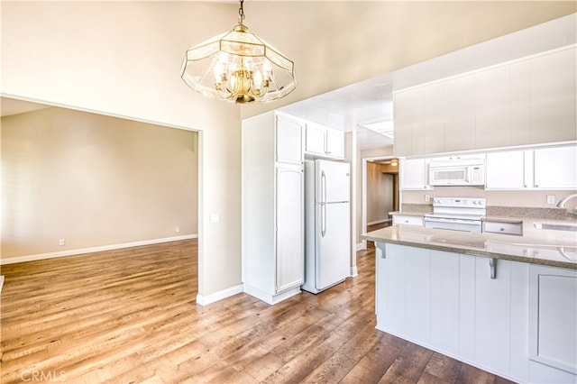 kitchen with white cabinets, hardwood / wood-style flooring, kitchen peninsula, and white appliances