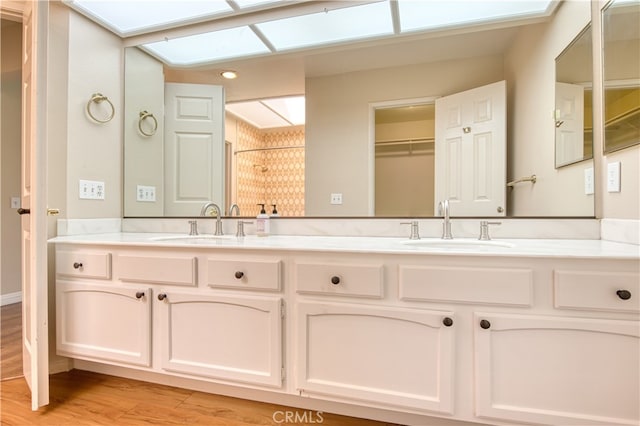 bathroom featuring wood-type flooring, vanity, and a skylight