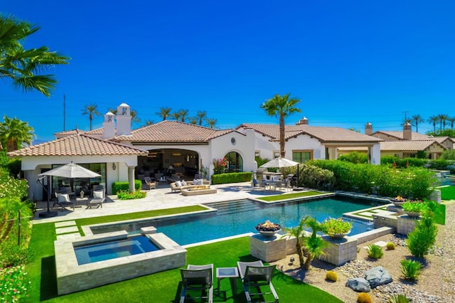 rear view of property with a patio and a pool with hot tub