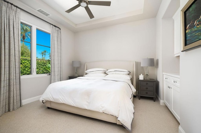 carpeted bedroom featuring ceiling fan and a tray ceiling