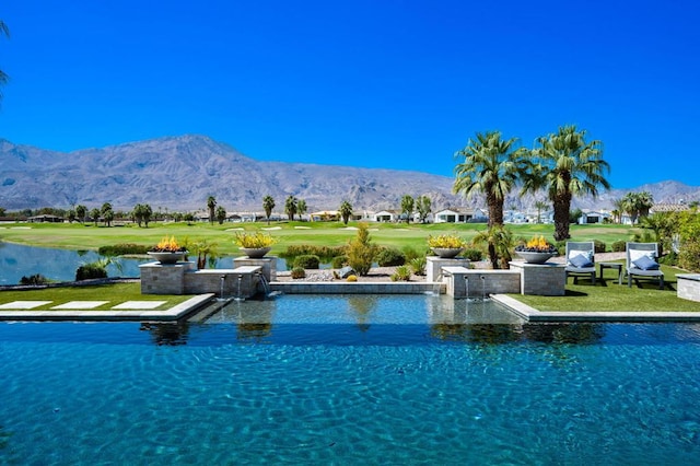 view of pool with a lawn and a water and mountain view