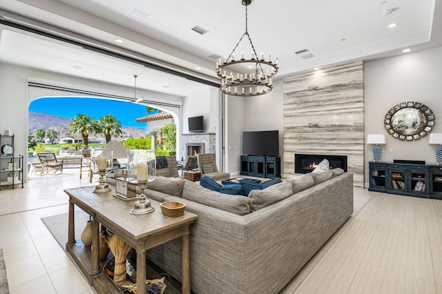 tiled living room featuring a large fireplace and an inviting chandelier