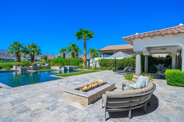 view of swimming pool with ceiling fan, a patio, and a fire pit