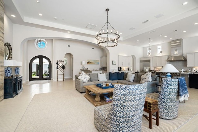 living room featuring a towering ceiling, french doors, light tile patterned floors, and an inviting chandelier