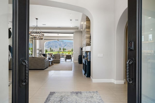 corridor featuring a mountain view, light tile patterned floors, and a chandelier