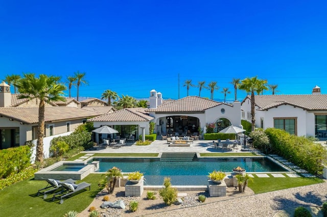 back of house with outdoor lounge area, a patio, and a pool with hot tub