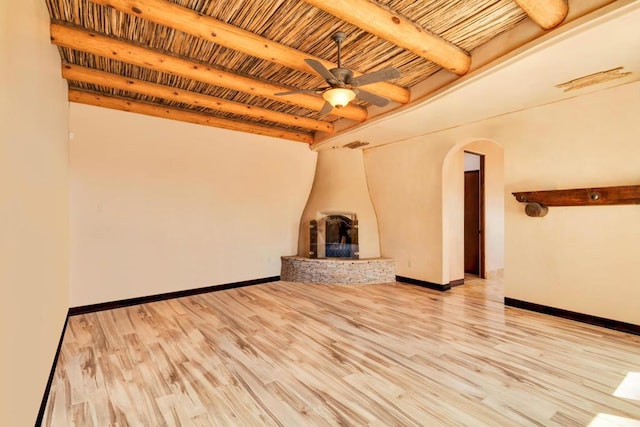 unfurnished living room with wooden ceiling, light hardwood / wood-style flooring, ceiling fan, a fireplace, and beam ceiling