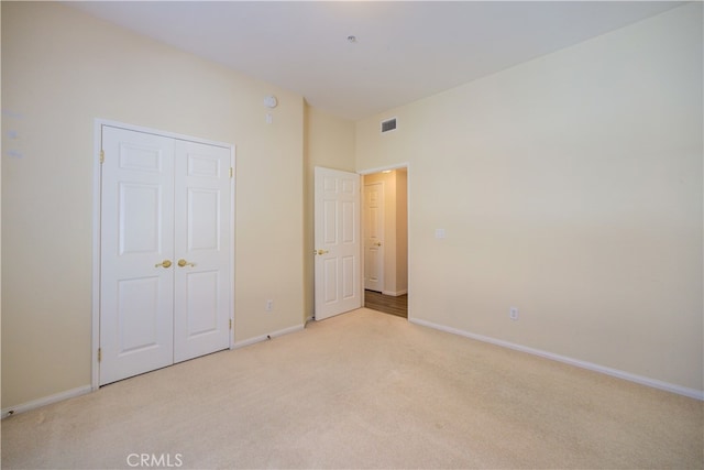 unfurnished bedroom featuring a closet and light colored carpet