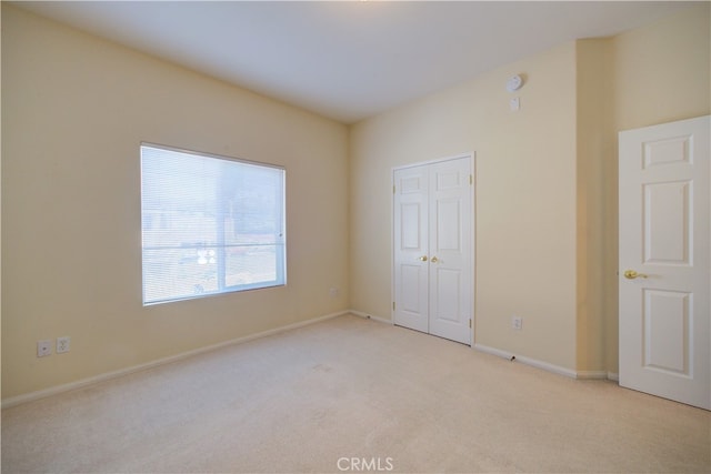 unfurnished bedroom with light carpet and a closet