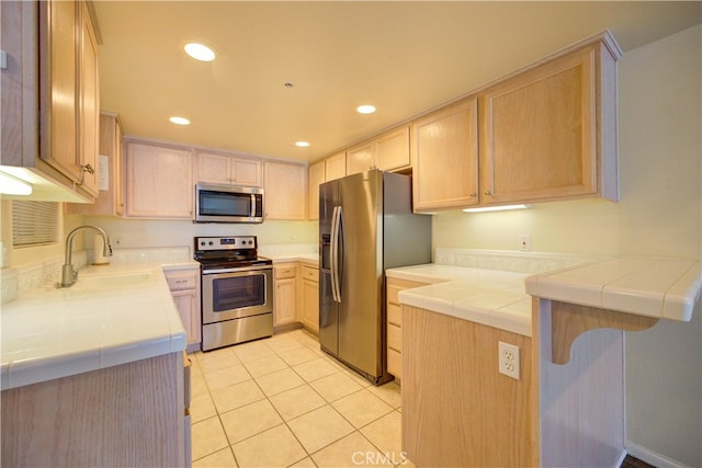 kitchen featuring sink, kitchen peninsula, stainless steel appliances, tile countertops, and light brown cabinetry