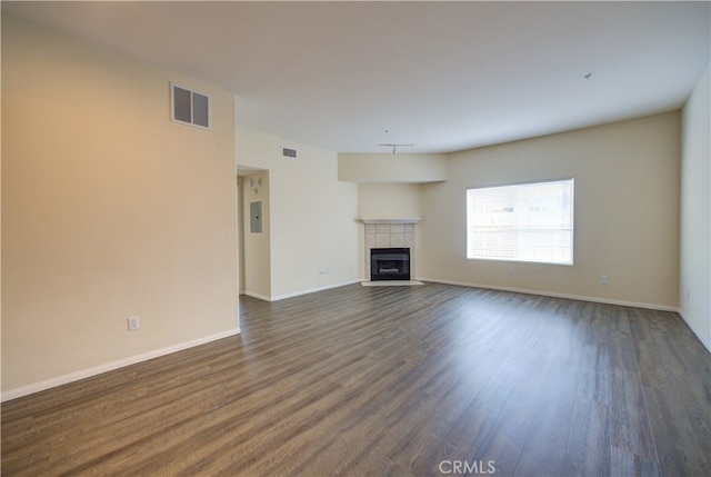 unfurnished living room with dark hardwood / wood-style flooring and a tile fireplace