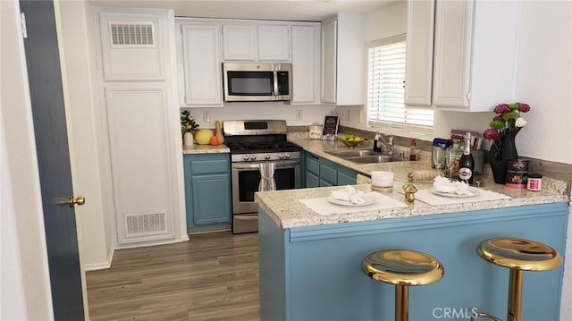 kitchen with white cabinetry, sink, stainless steel appliances, dark wood-type flooring, and kitchen peninsula