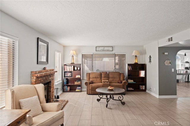 living room featuring a brick fireplace, a textured ceiling, and light hardwood / wood-style flooring