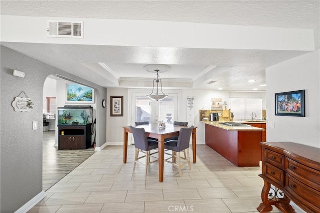 dining space with a textured ceiling, a raised ceiling, and sink