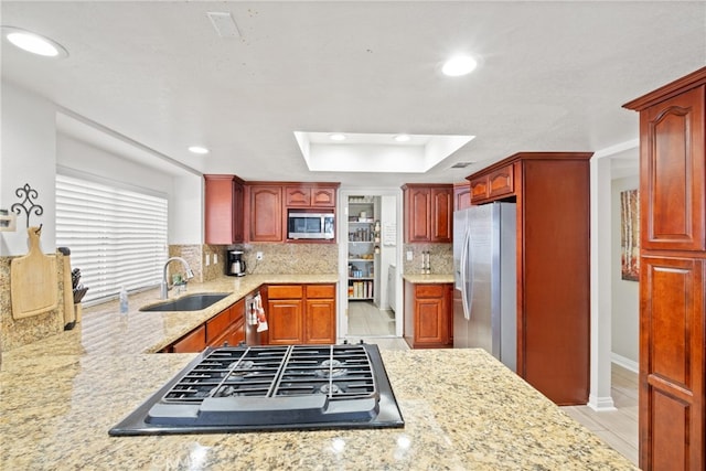 kitchen with appliances with stainless steel finishes, decorative backsplash, light hardwood / wood-style floors, kitchen peninsula, and sink